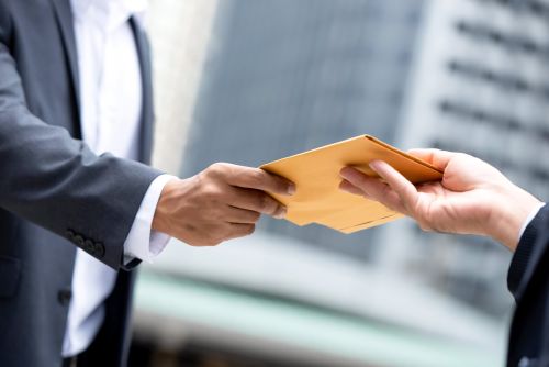 close up portrait businessman hand recieving yellow envelope from boss urban city background min scaled 742954aa